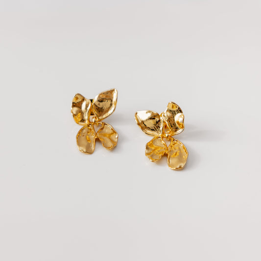 Gold bow-shaped earrings on a light gray background
