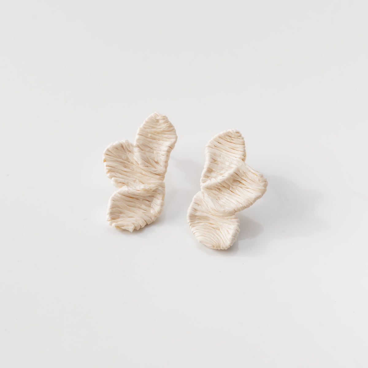 Pair of white and gold earrings on a light gray background