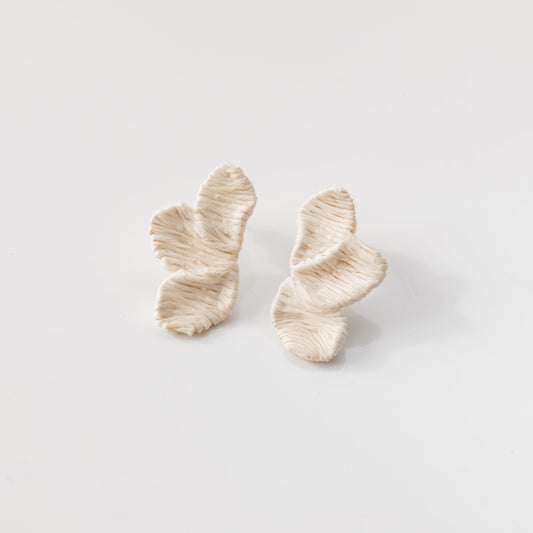 Pair of white and gold earrings on a light gray background