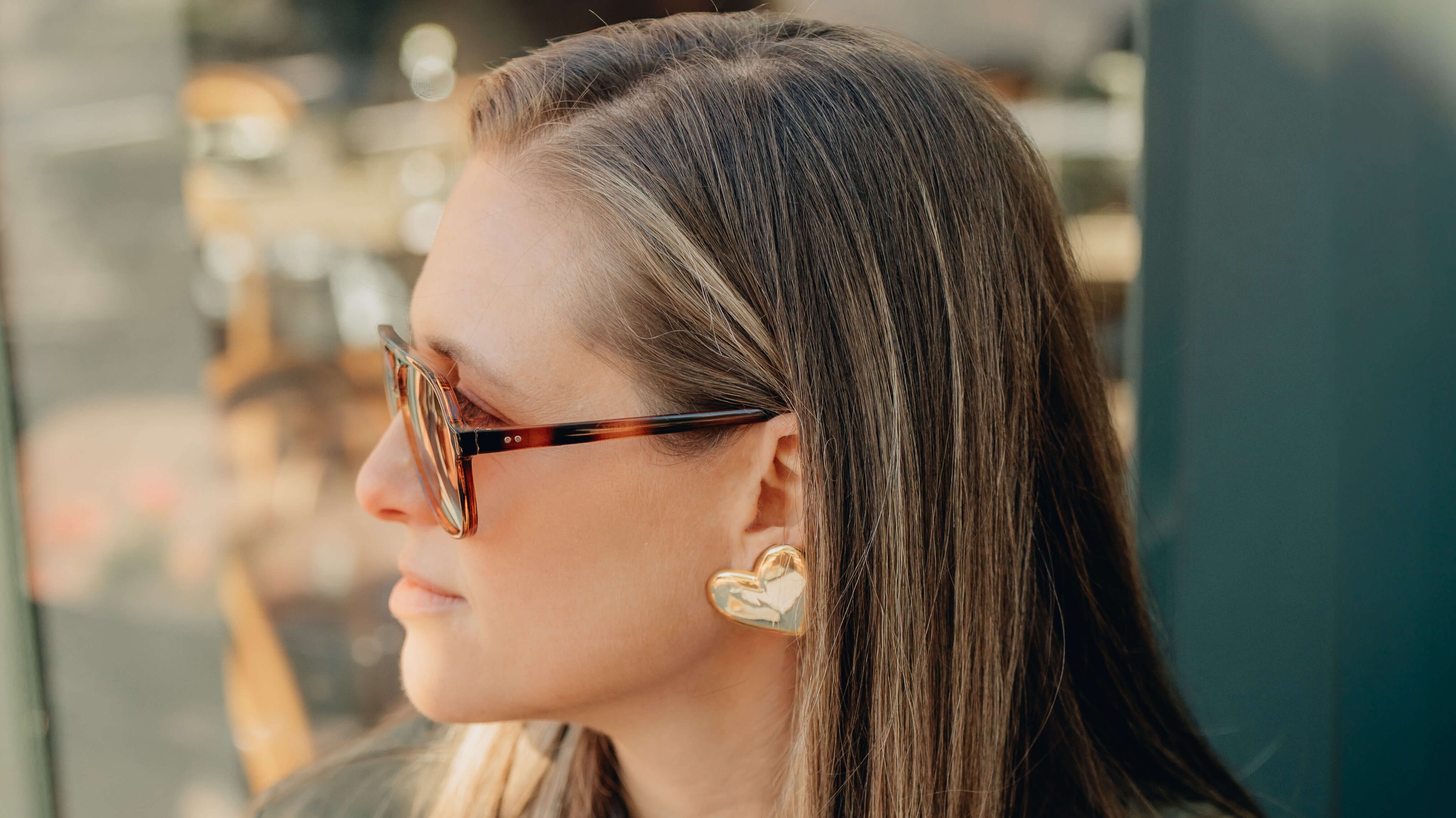 Woman wearing sunglasses and heart-shaped earrings with a blurred background