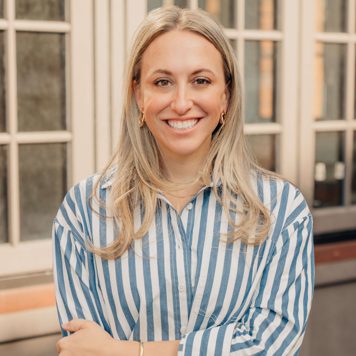 Woman with blonde hair wearing a blue shirt sitting on a beige couch.