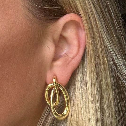 Gold double loop earring worn by a person with blonde hair.