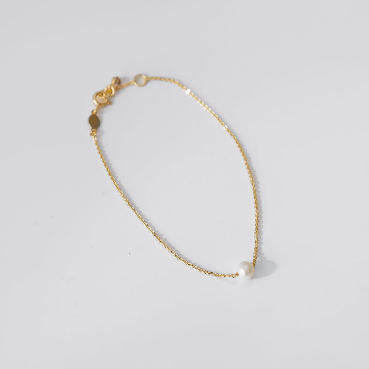 Gold pearl bracelet on a light gray background