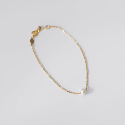 Gold pearl bracelet on a light gray background