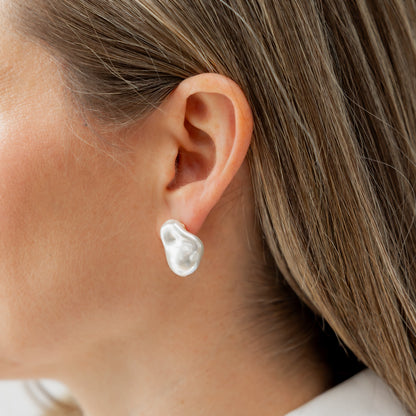 Close-up of a person wearing a pearl earring with a blurred background