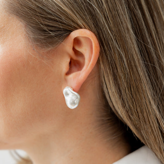Close-up of a person wearing a pearl earring with a blurred background