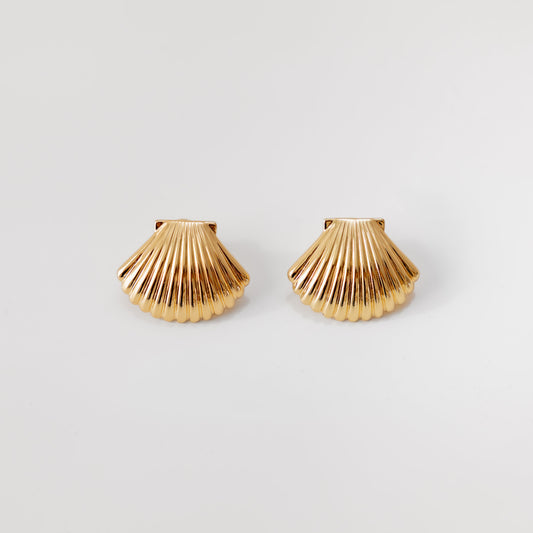 Gold shell-shaped earrings on a light gray background
