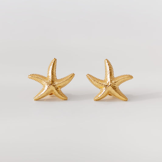 Gold starfish earrings on a light gray background